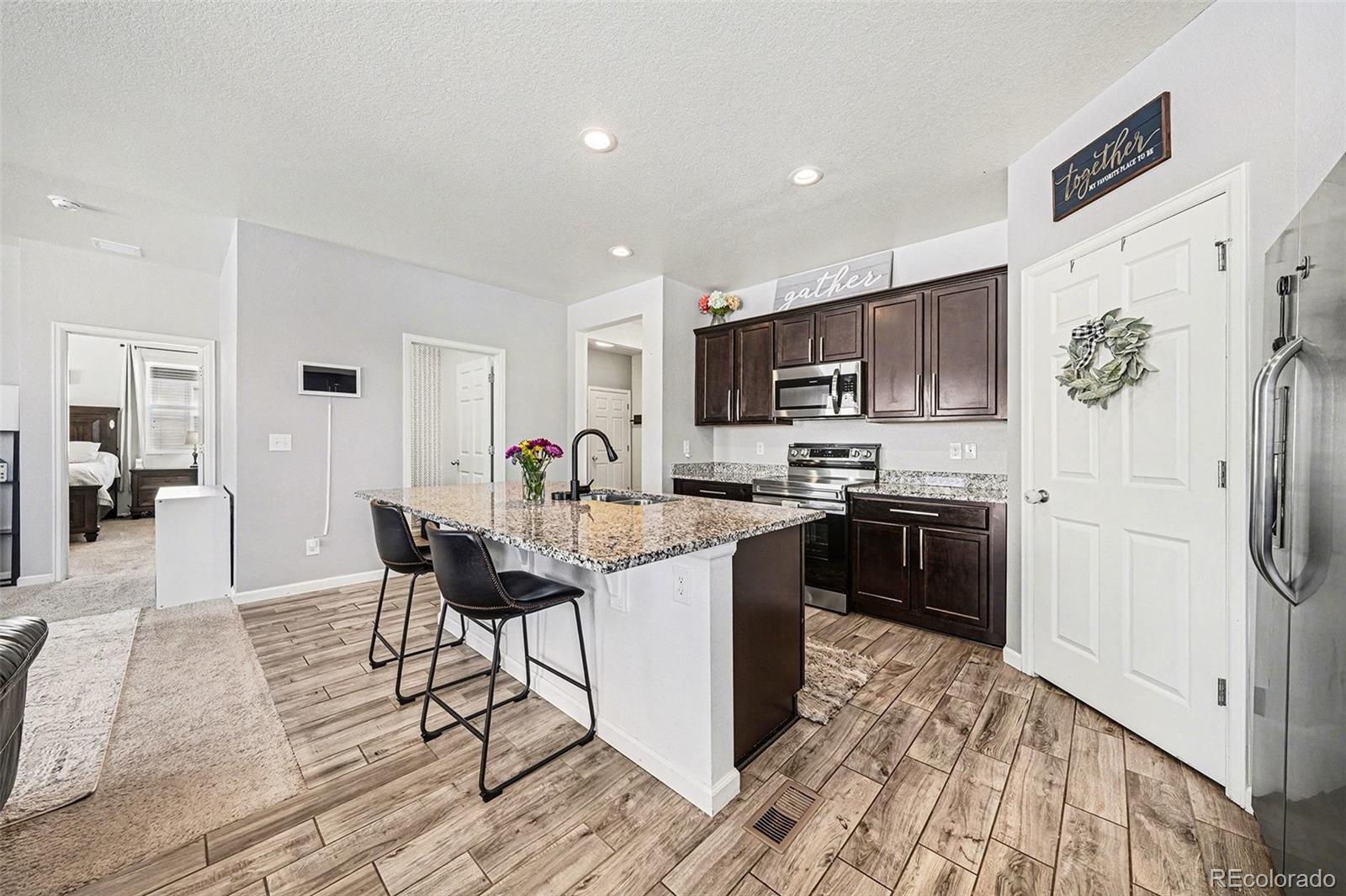 910 Pierson Court Windsor, CO 80550 - Photo 7 of 42 a kitchen with stainless steel appliances kitchen island granite countertop a refrigerator and a stove top oven