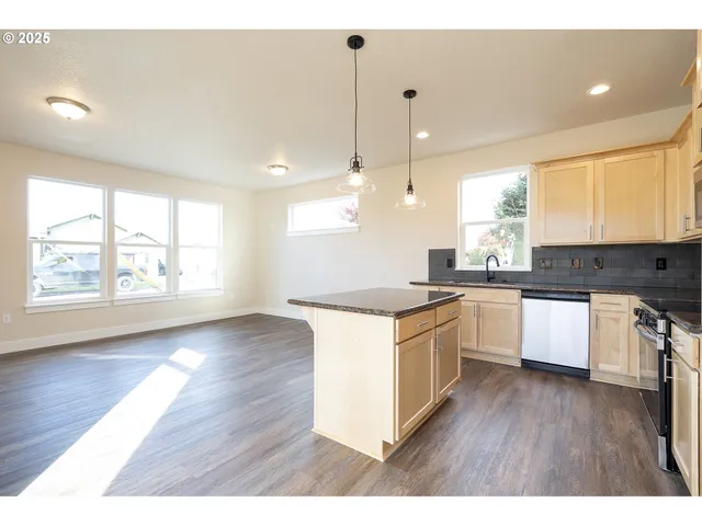 a large kitchen with granite countertop a stove top oven a sink a counter space and wooden floor