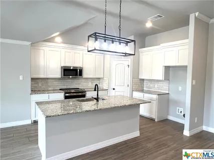 a kitchen with stainless steel appliances granite countertop a sink stove and microwave