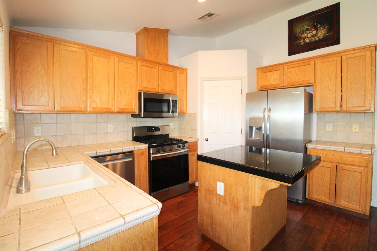 554 St Michelle Drive Madera, CA 93637 - Photo 7 of 19 a kitchen with stainless steel appliances granite countertop a sink a stove and a refrigerator