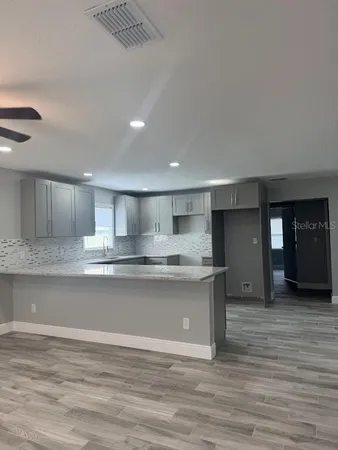 a view of kitchen with kitchen island a sink wooden floor and a refrigerator