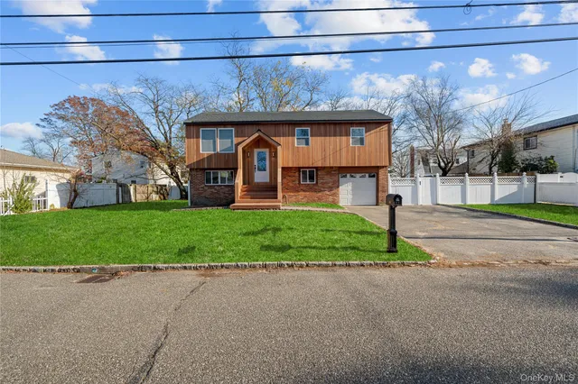 a view of a brick house with a big yard plants and large trees