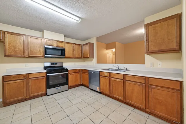 a kitchen with stainless steel appliances a stove a sink and a refrigerator