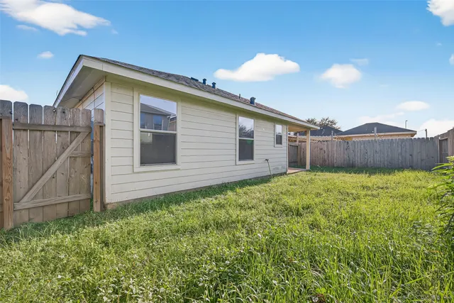 a view of backyard with large trees and wooden fence