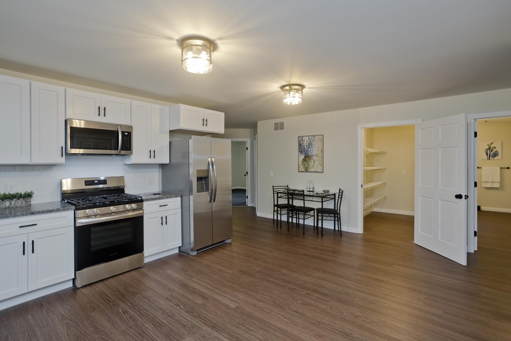 2089 Oak Street Three Rivers, MA 01080 - Photo 6 of 42 a kitchen with stainless steel appliances granite countertop a stove top oven a sink dishwasher a dining table and chairs with wooden floor