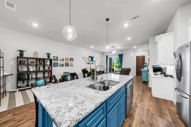 a kitchen with stainless steel appliances kitchen island granite countertop a kitchen island a stove a refrigerator a sink a dining table and chairs with wooden floor