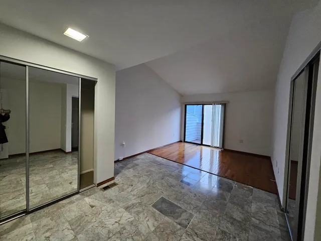 an empty room with wooden floor and natural light
