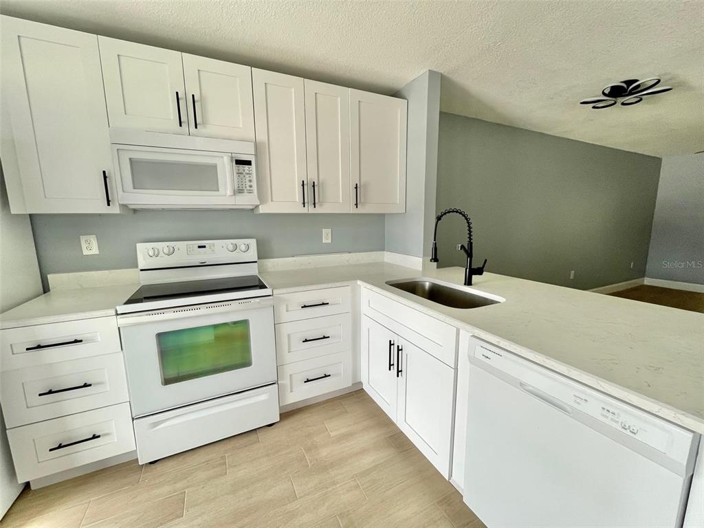 2852 Stillwell Court New Port Richey, FL 34655 - Photo 3 of 13 a kitchen with white cabinets and white appliances