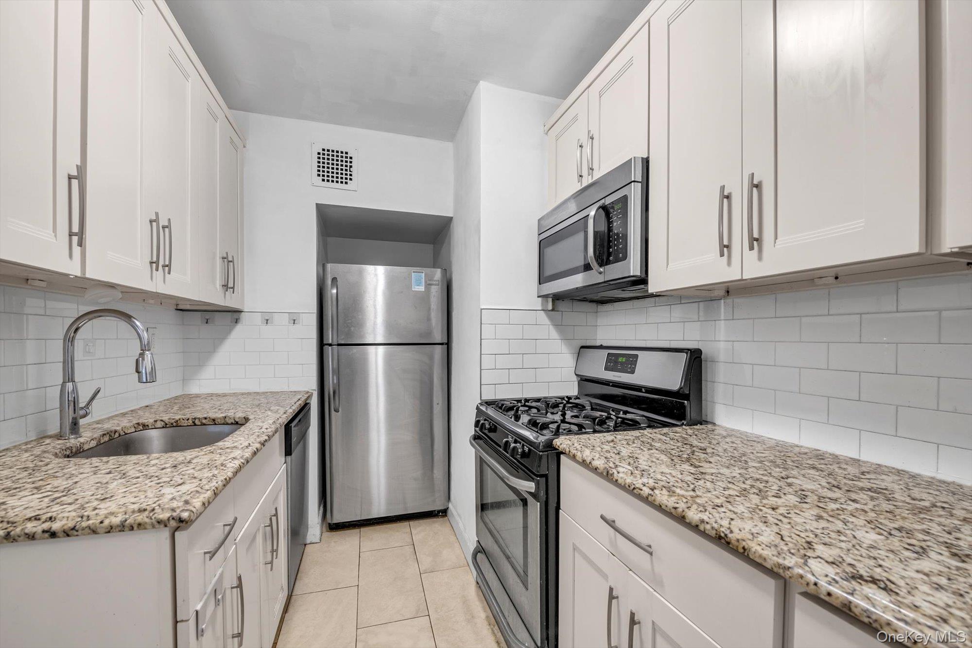139-15 83rd Avenue, Unit 305 Queens, NY 11435 - Photo 12 of 21 a kitchen with granite countertop stainless steel appliances and white cabinets