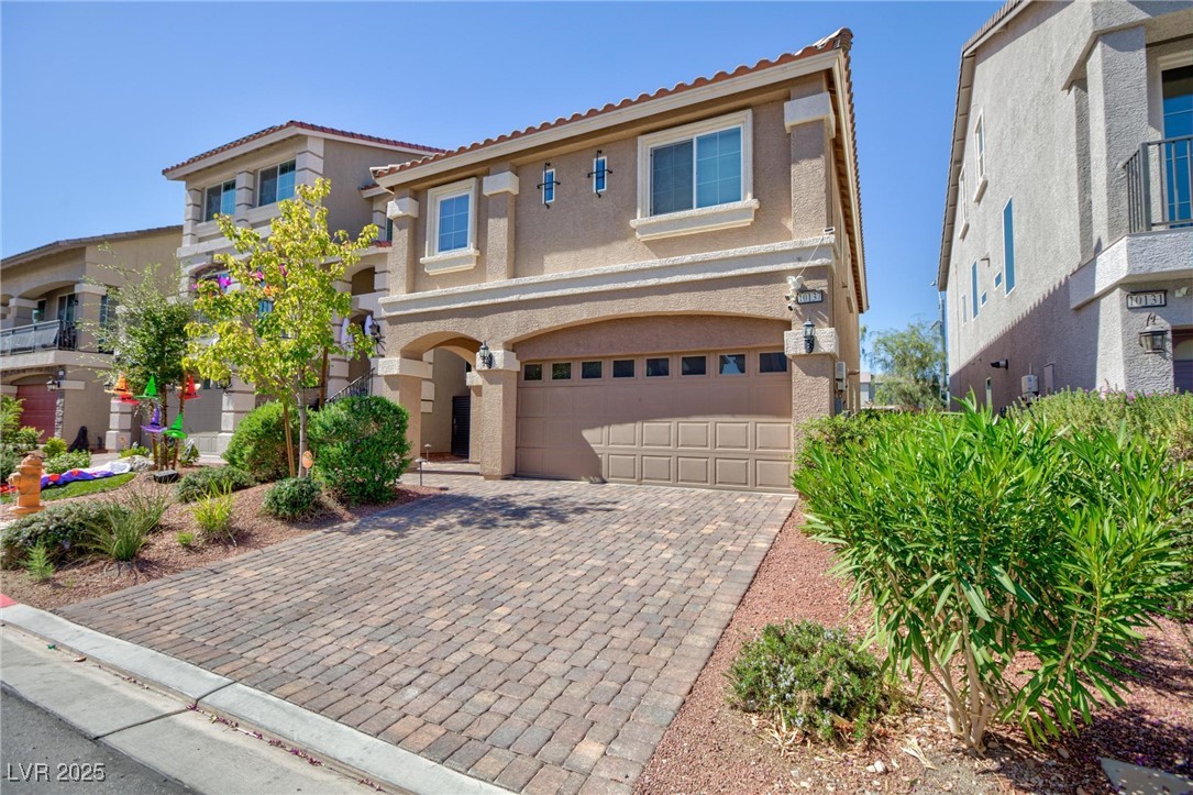 10137 Herons Rise Street Las Vegas, NV 89141 - Photo 3 of 38 Mediterranean / spanish-style house featuring stucco siding, a tiled roof, decorative driveway, and a garage