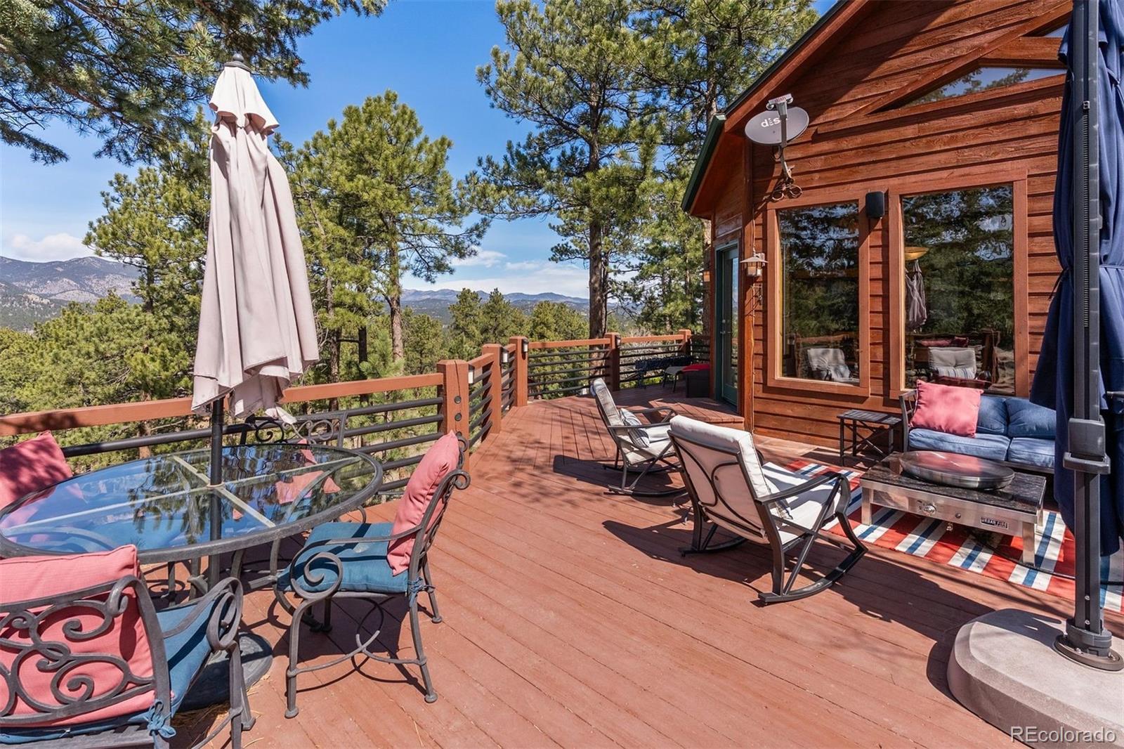 5811 Herzman Drive Evergreen, CO 80439 - Photo 13 of 49 a view of a patio with table and chairs and floor to ceiling window plants and trees
