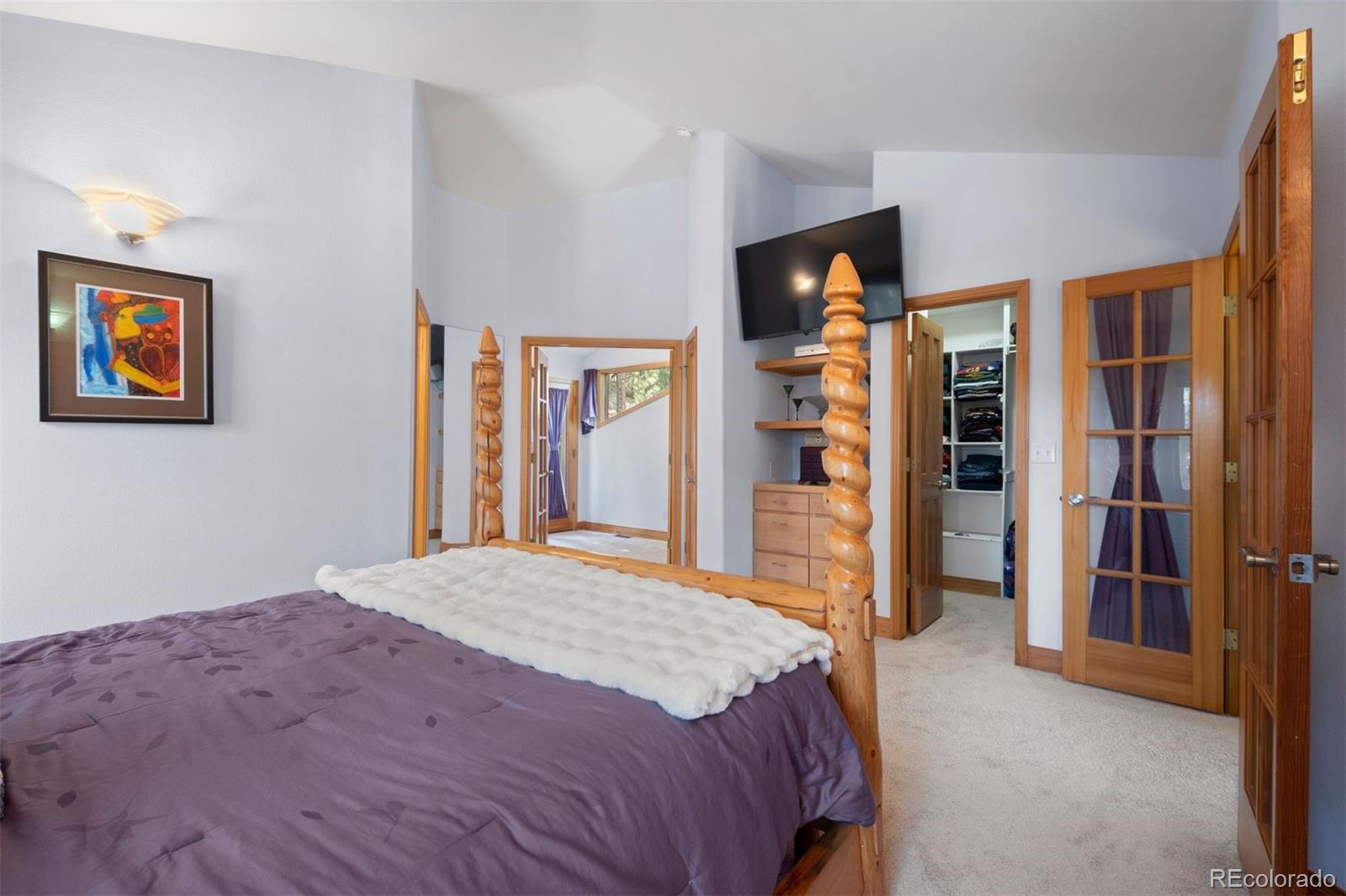 5811 Herzman Drive Evergreen, CO 80439 - Photo 23 of 49 a bedroom with a bed and a flat screen tv