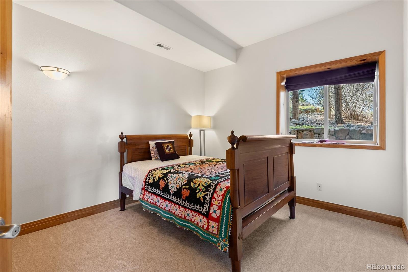 5811 Herzman Drive Evergreen, CO 80439 - Photo 32 of 49 a bed sitting in a bedroom next to a window