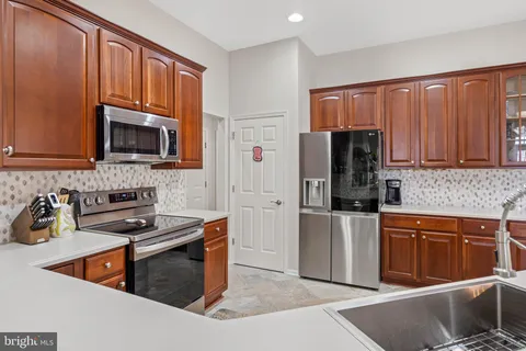 a kitchen with stainless steel appliances granite countertop a stove a sink dishwasher a refrigerator and a microwave oven with wooden cabinets