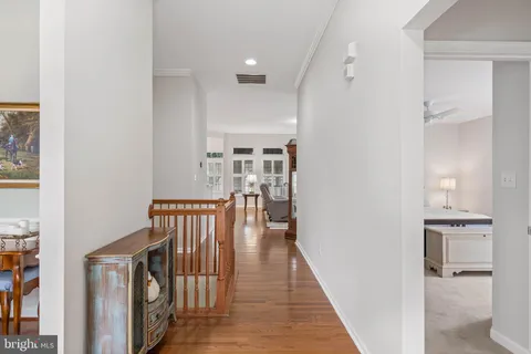 a view of a hallway with wooden floor and a bathroom