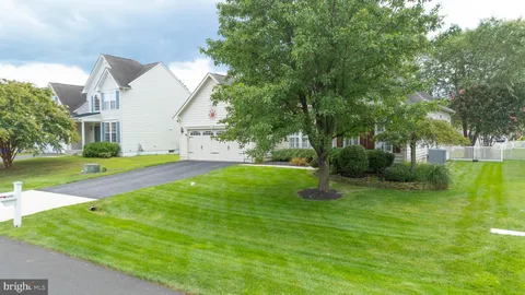 a view of a white house with a big yard and large trees