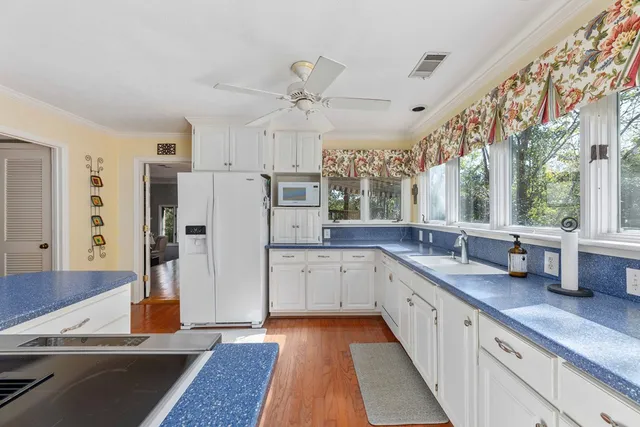 a kitchen with stainless steel appliances granite countertop a stove a refrigerator a kitchen island with white cabinets and wooden floor