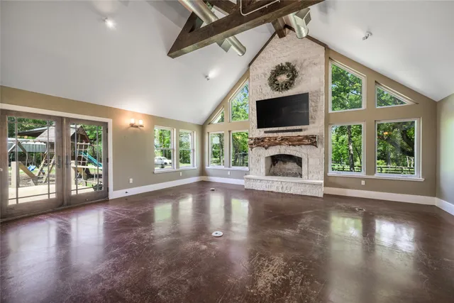 a view of an empty room with wooden floor fireplace and a window