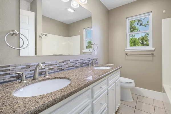 a bathroom with a granite countertop sink a toilet and a mirror
