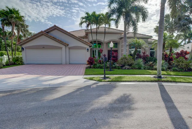 a view of a house with a yard and palm trees