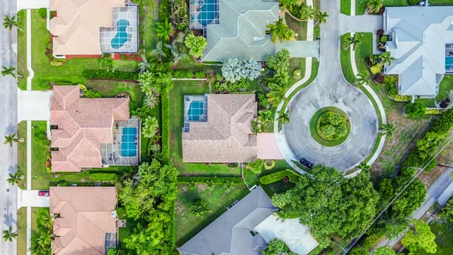 an aerial view of residential houses with outdoor space and trees all around