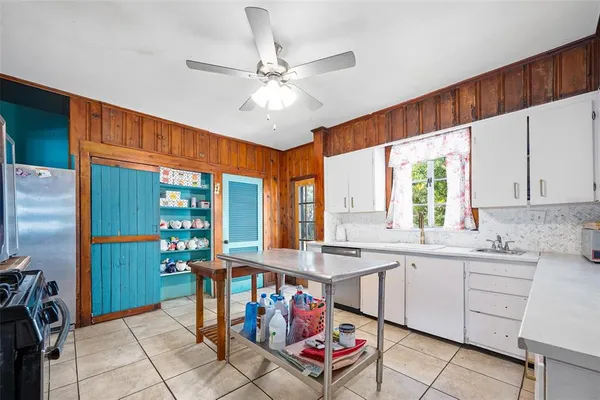 a open kitchen with stainless steel appliances kitchen island granite countertop a refrigerator a stove a sink dishwasher and white cabinets with wooden floor
