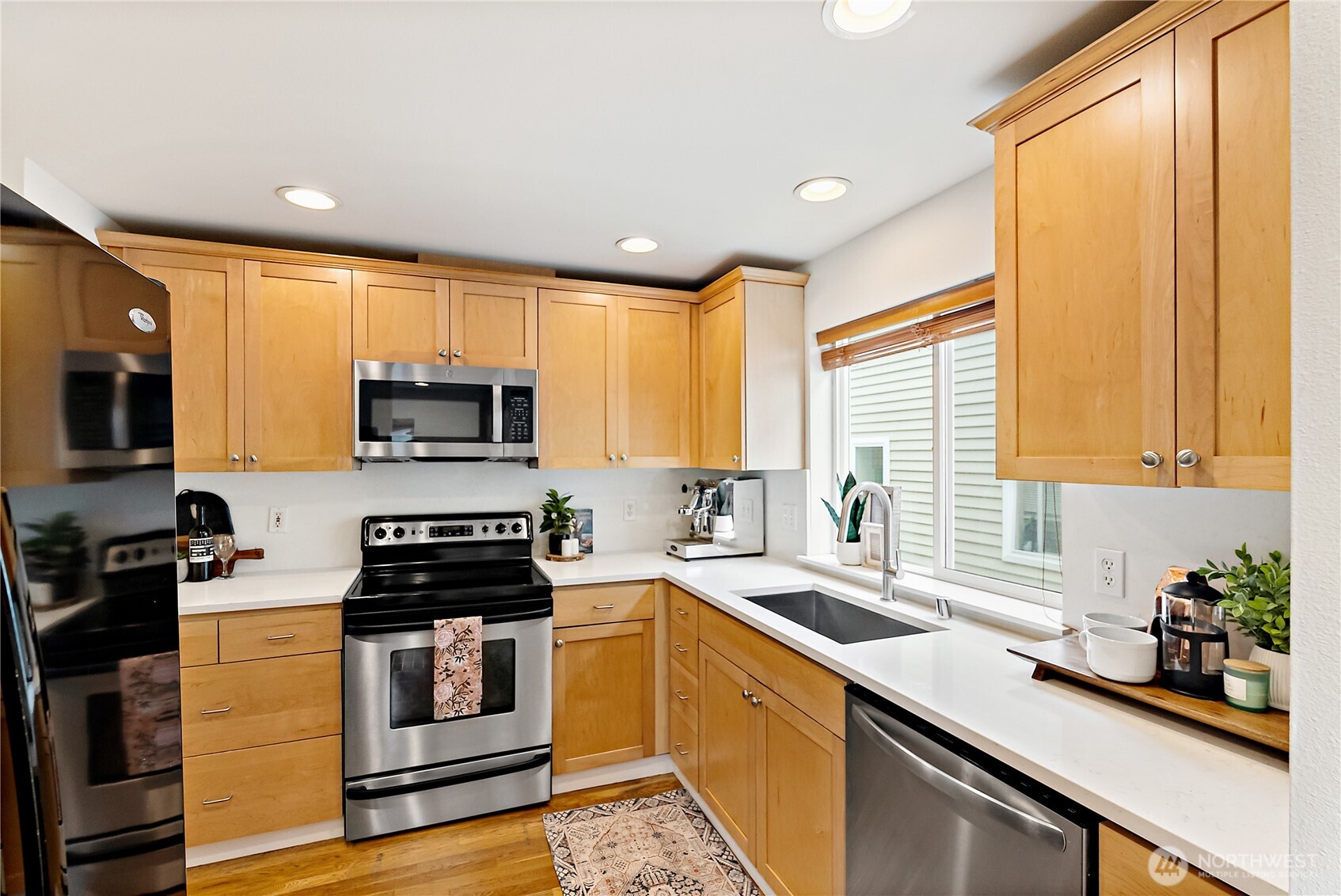 9239 Ashworth Avenue North, Unit B Seattle, WA 98103 - Photo 19 of 40 a kitchen with stainless steel appliances a sink a stove a microwave and cabinets