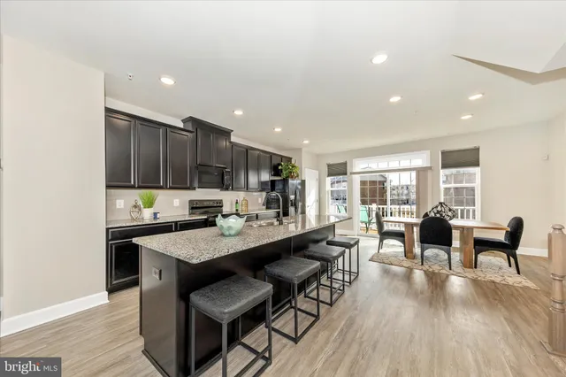 a large dining hall with stainless steel appliances granite countertop a stove and a dining table with wooden floor