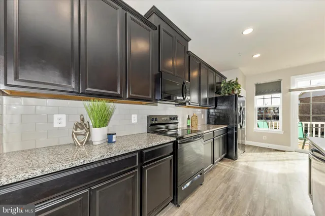 a kitchen with granite countertop stainless steel appliances a sink stove top oven and cabinets