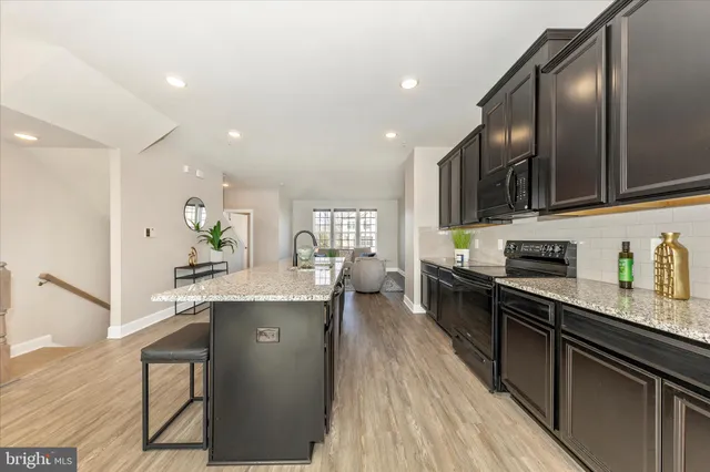 a kitchen with stainless steel appliances granite countertop a stove top oven a sink dishwasher a dining table and chairs with wooden floors