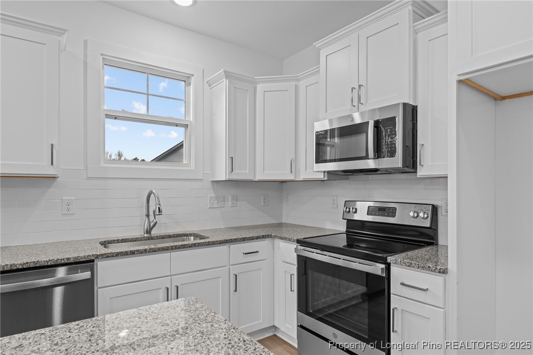 144 Vorster Road Raeford, NC 28376 - Photo 11 of 35 a kitchen with stainless steel appliances granite countertop white cabinets a stove a microwave and a sink