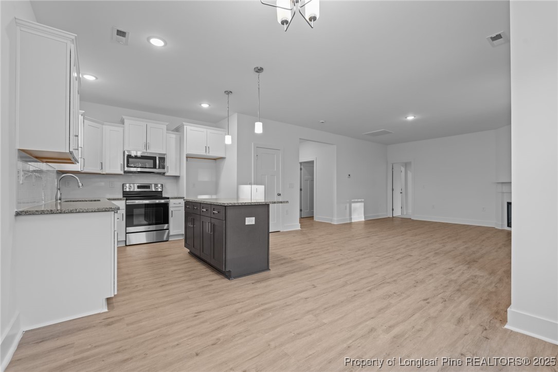 144 Vorster Road Raeford, NC 28376 - Photo 13 of 35 a kitchen with stainless steel appliances granite countertop a stove top oven a sink and white cabinets