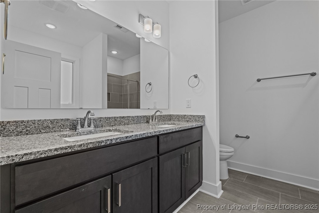 144 Vorster Road Raeford, NC 28376 - Photo 16 of 35 a bathroom with a granite countertop sink a toilet and a mirror