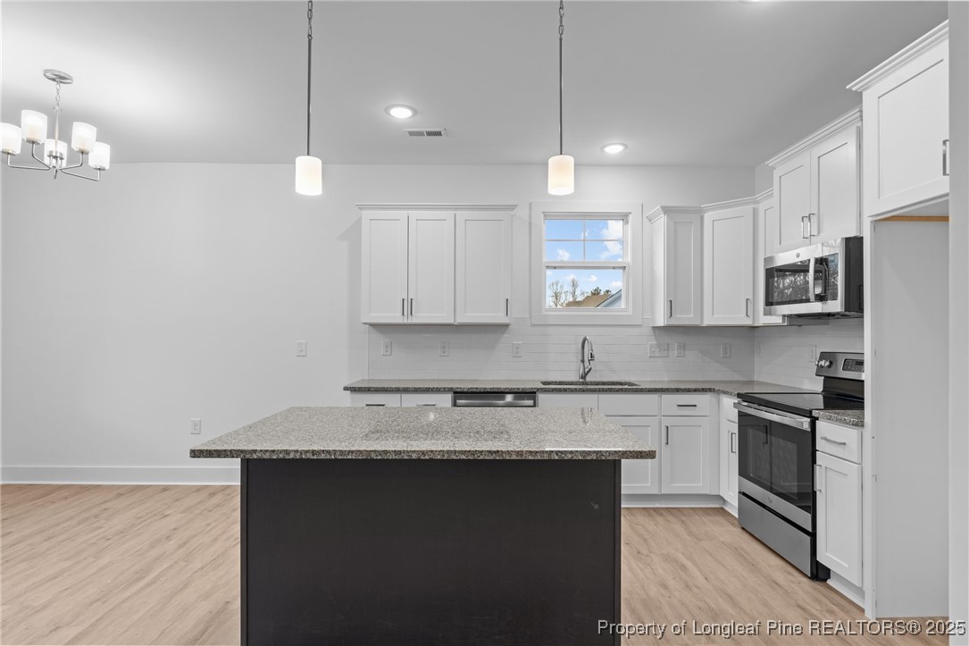 144 Vorster Road Raeford, NC 28376 - Photo 9 of 35 a kitchen with kitchen island granite countertop a sink a stove a oven a refrigerator and white cabinets