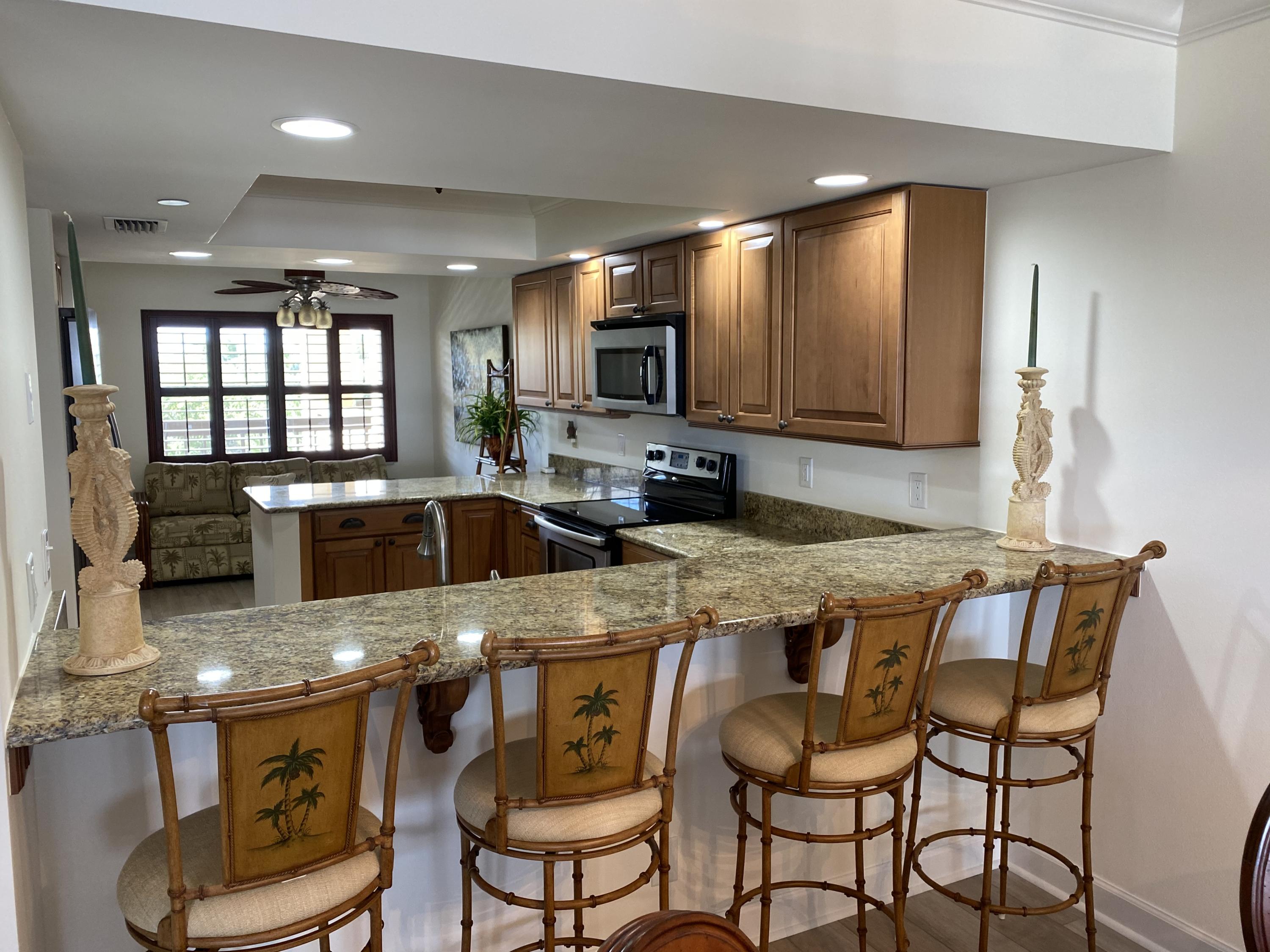 1055 Ocean Drive, Unit 403 Juno Beach, FL 33408 - Photo 3 of 28 a kitchen with stainless steel appliances granite countertop a stove a sink a microwave a dining table and chairs