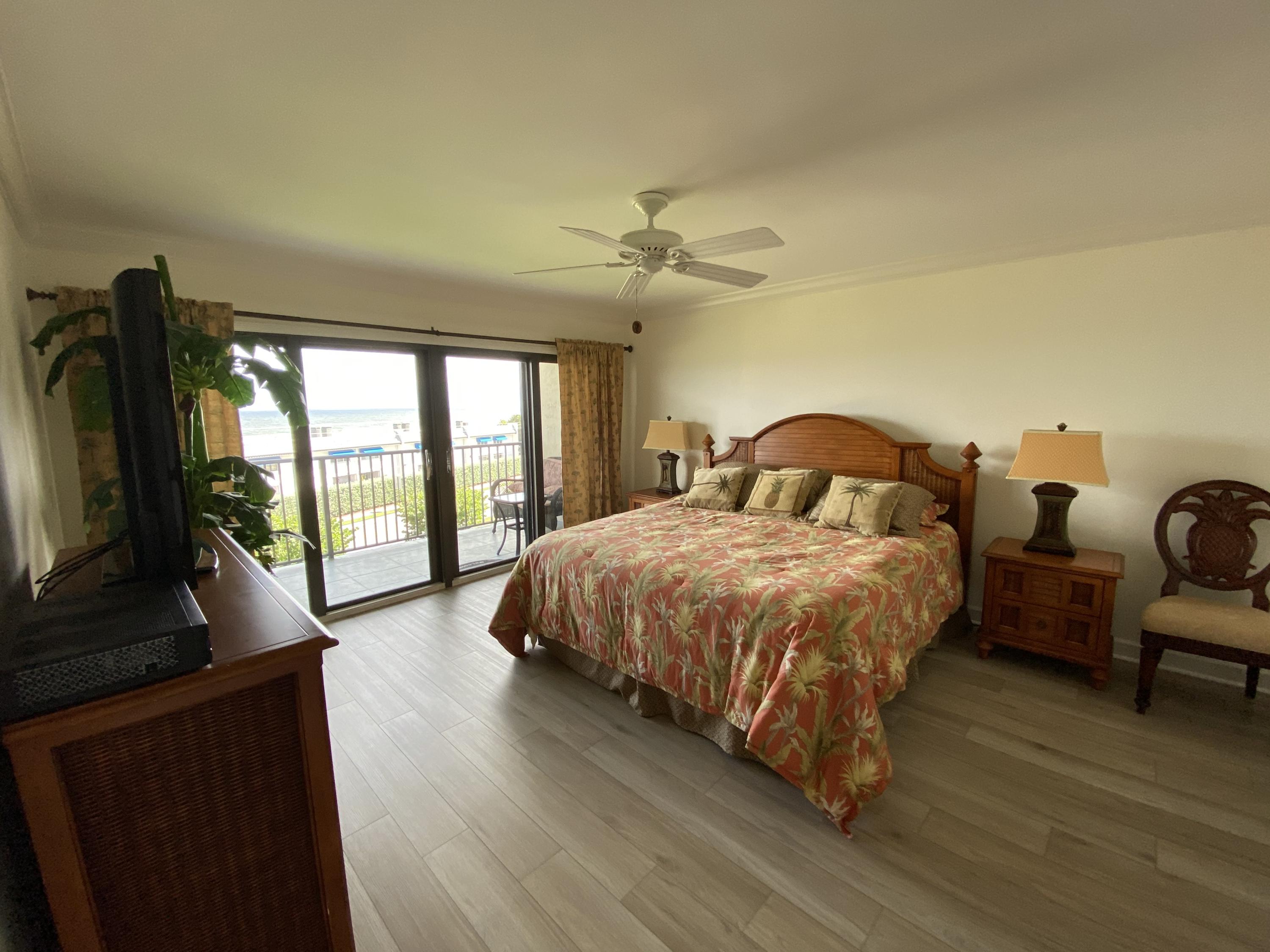 1055 Ocean Drive, Unit 403 Juno Beach, FL 33408 - Photo 7 of 28 a spacious bedroom with a bed and a flat tv screen on dresser