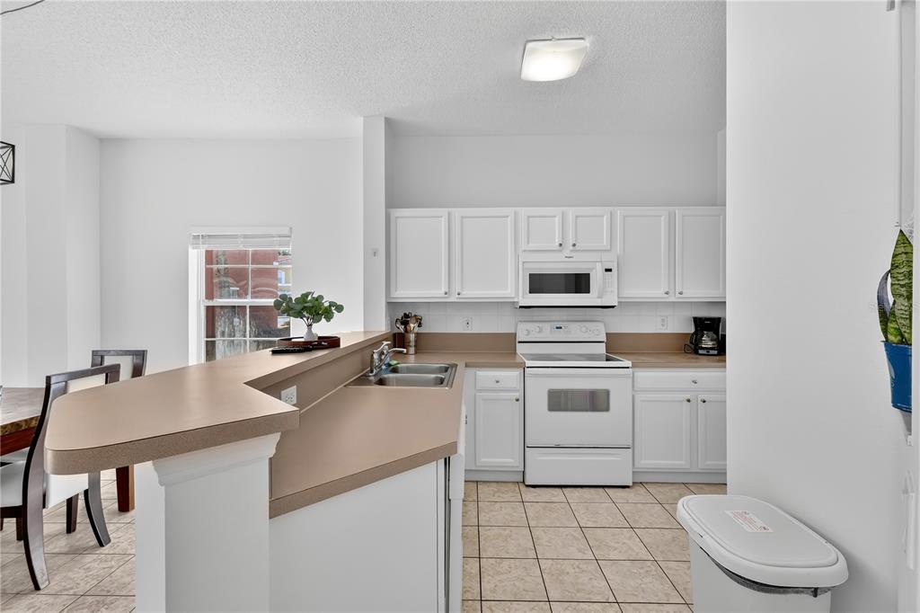 1070 Park Ridge Circle Kissimmee, FL 34746 - Photo 6 of 36 a kitchen with a sink a stove and chairs