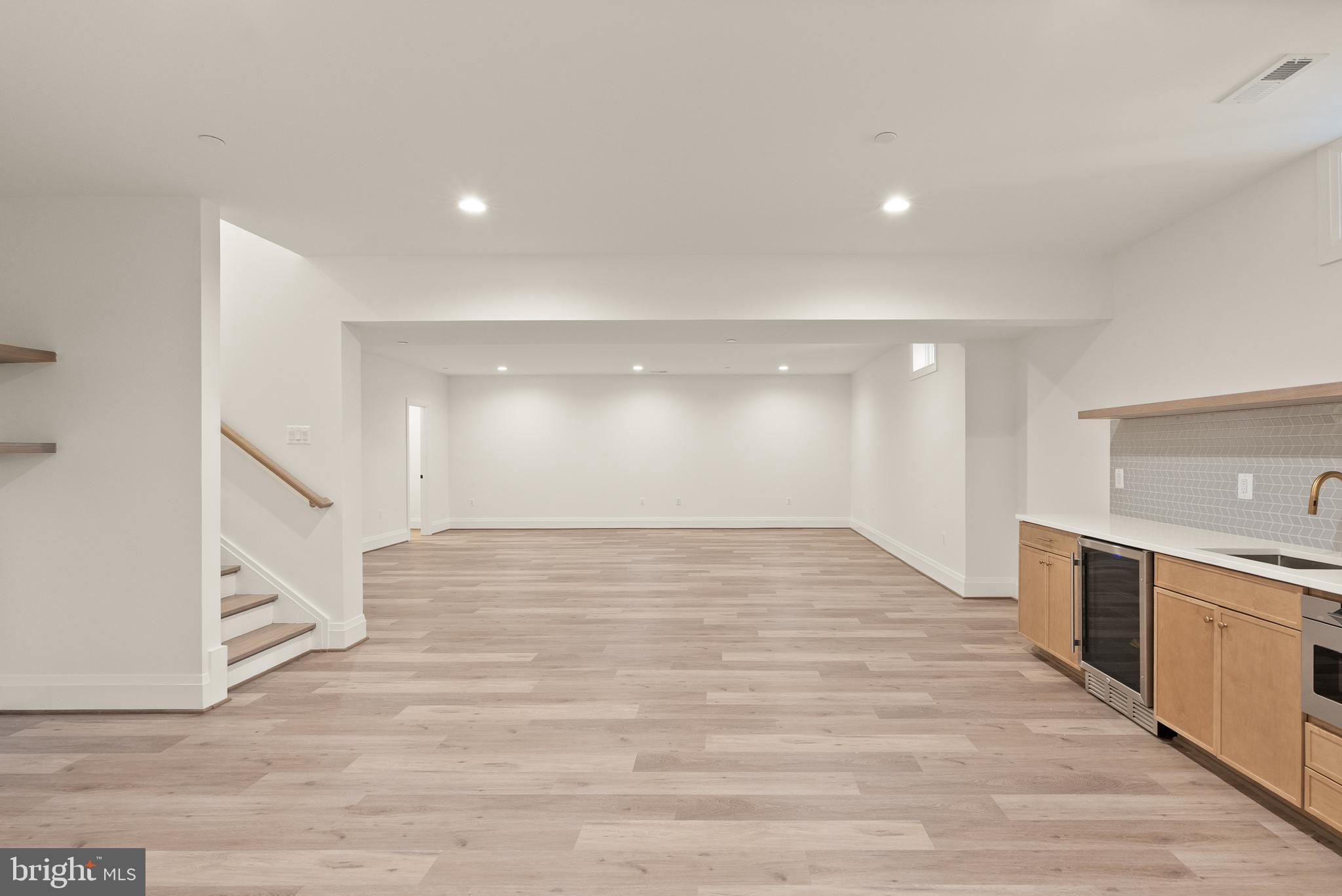 7806 Carteret Road Bethesda, MD 20817 - Photo 48 of 58 a view of an empty room with wooden floor and a kitchen