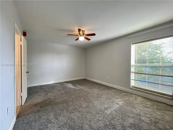 an empty room with windows and ceiling fan