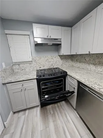 a kitchen with granite countertop a stove and cabinets