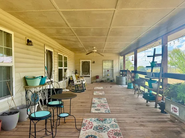 a view of a patio with table and chairs potted plants with wooden floor and fence
