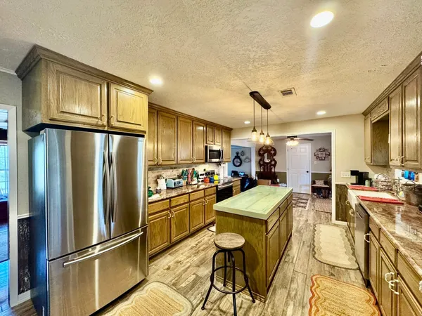 a kitchen with granite countertop a refrigerator and microwave