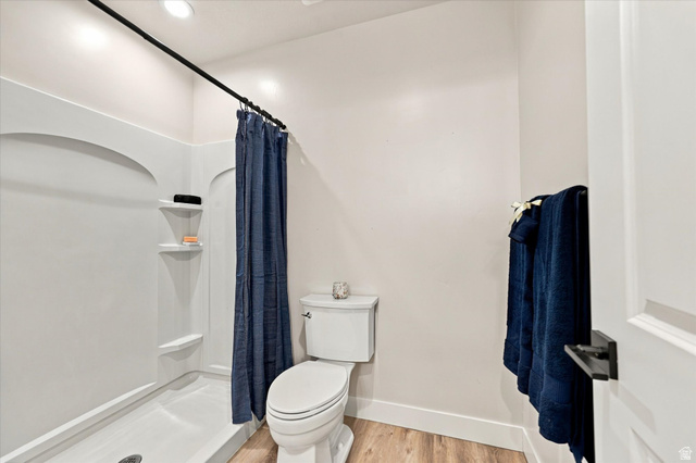 754 West 400 North Mapleton, UT 84664 - Photo 55 of 86 Integrated shower with built-in shelving, white toilet, wood-finish flooring, and black hardware.