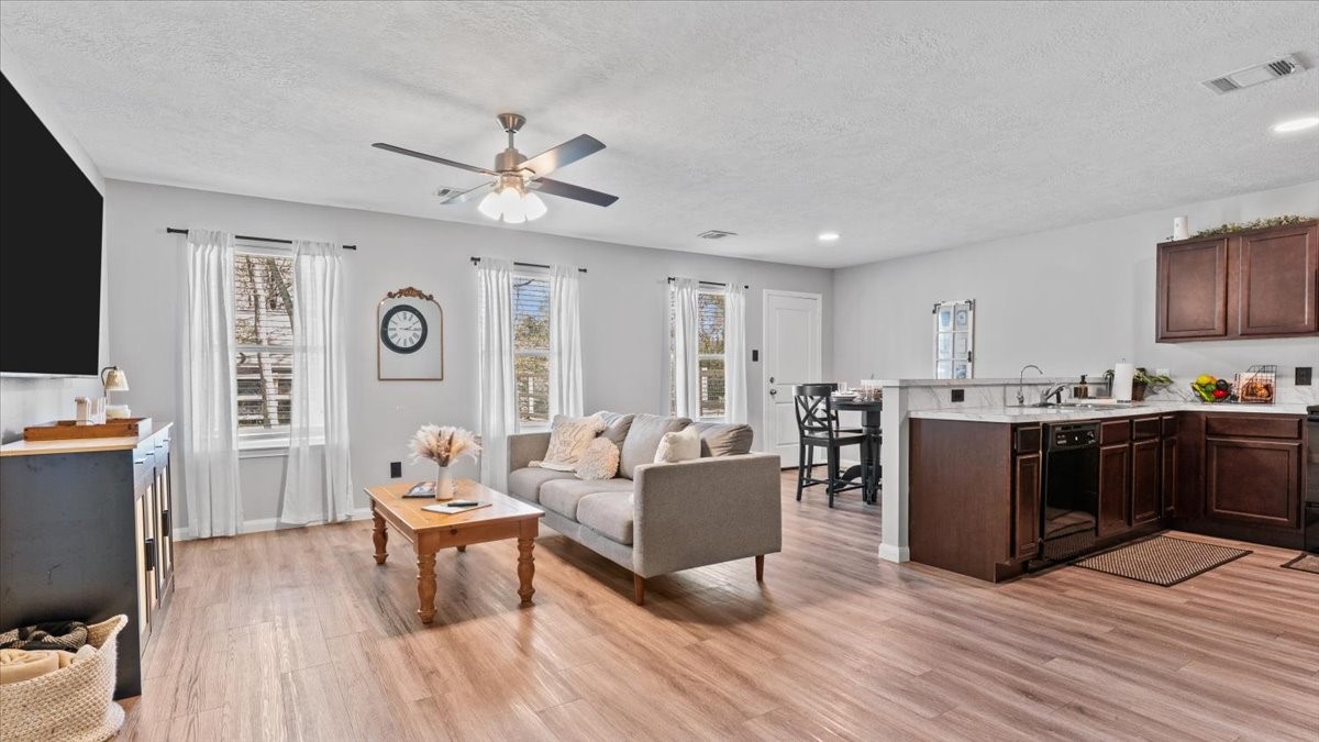 a living room with couches and kitchen view with wooden floor