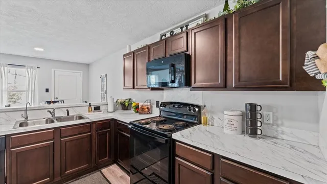 a kitchen with stainless steel appliances a sink dishwasher a stove top oven a refrigerator with wooden cabinets and floor