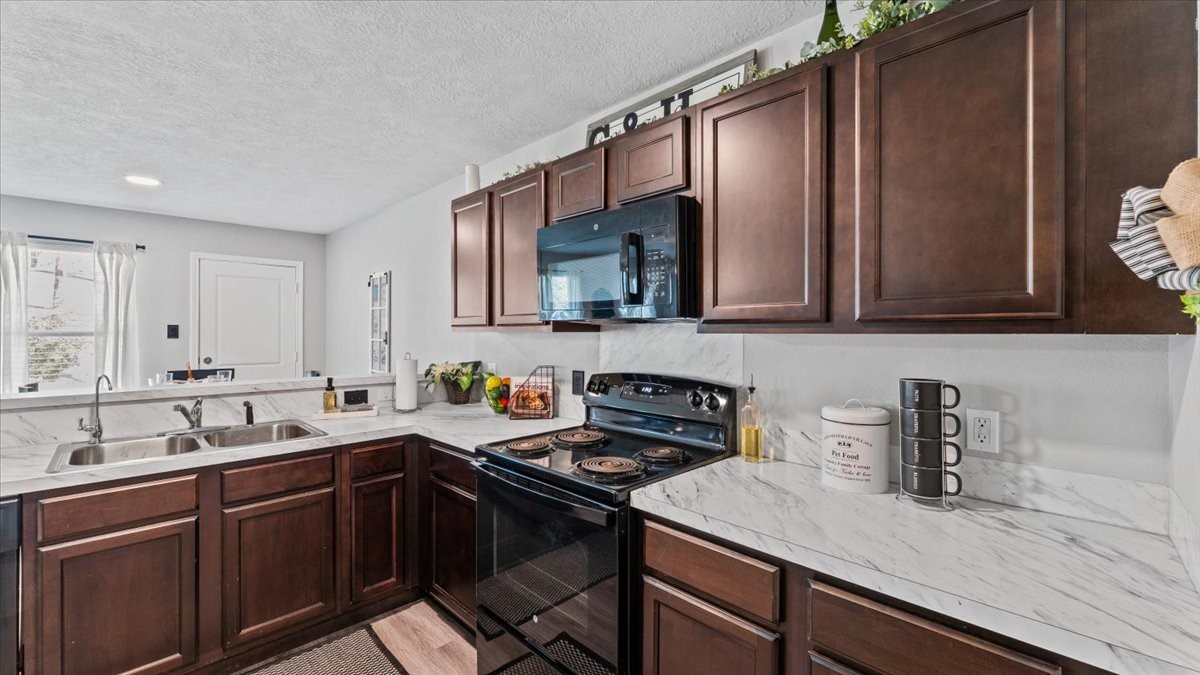 3975 Sam Houston Road Willis, TX 77378 - Photo 17 of 38 a kitchen with stainless steel appliances a sink dishwasher a stove top oven a refrigerator with wooden cabinets and floor