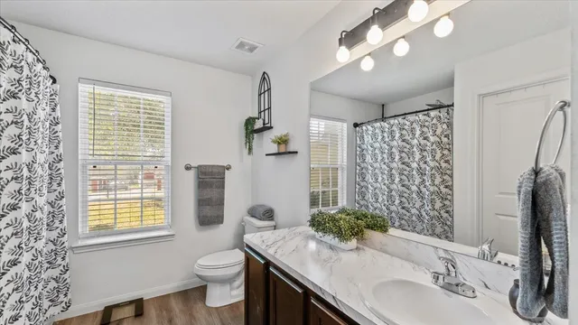 a bathroom with a granite countertop toilet a sink a shower and a mirror