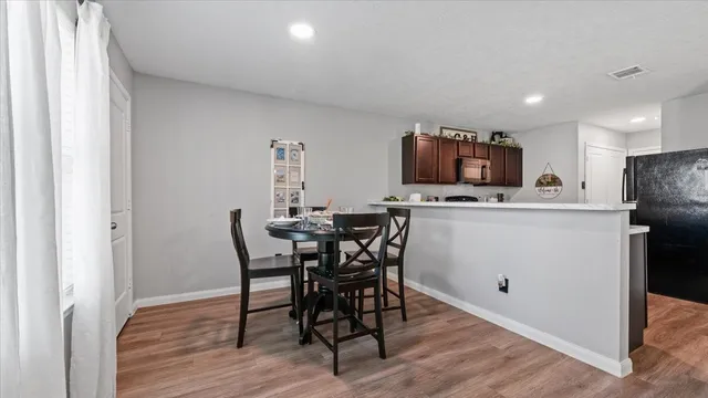 a kitchen with stainless steel appliances a dining table chairs and wooden floor