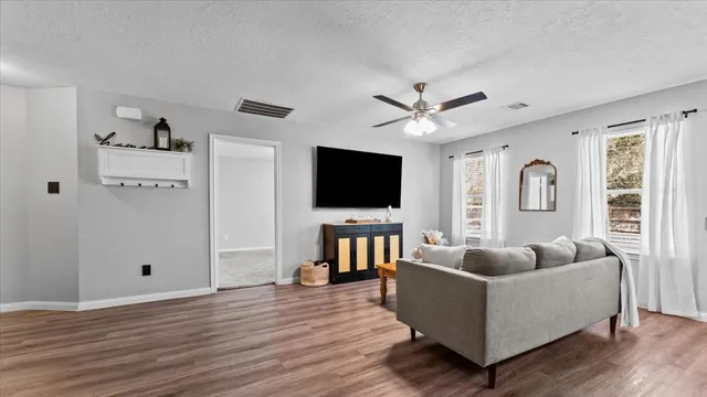 a living room with furniture ceiling fan and a flat screen tv