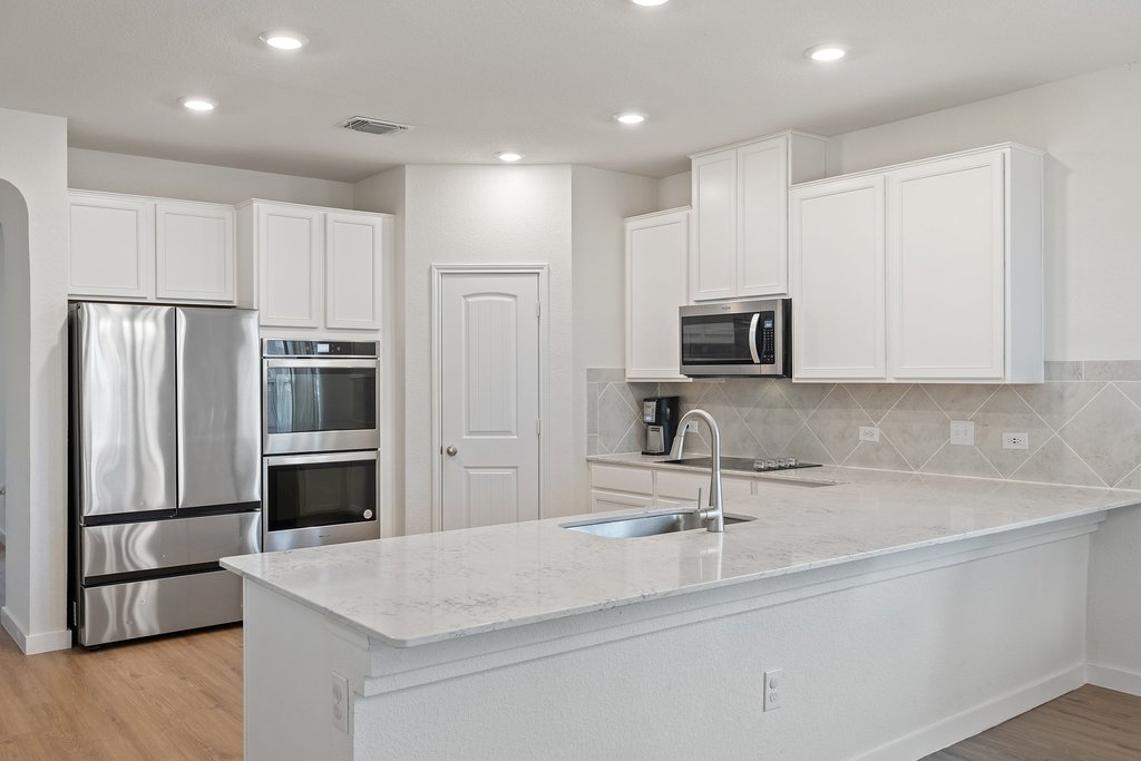 1926 Dragonfly Loop Bastrop, TX 78602 - Photo 6 of 33 Kitchen with abundant cabinet storage, double oven, light stone counters, and recessed lighting
